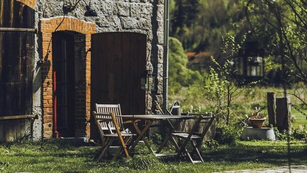 A rustic stone building with a brick archway, a wooden table, and chairs outside. - Nature Retreat near Janowice (Janowice Wielkie)