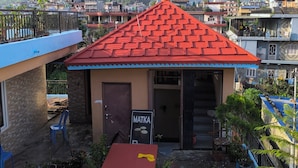 A small building with a red roof, a signboard, and potted plants.