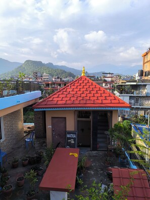 A small building with a red roof, a signboard, and potted plants.