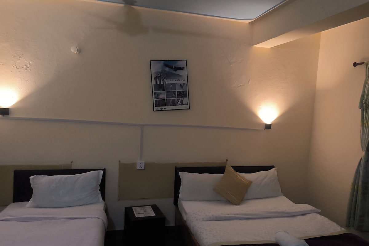 A hotel room with two beds, a wall-mounted light fixture, and a framed picture.