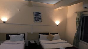 A hotel room with two beds, a wall-mounted light fixture, and a framed picture.