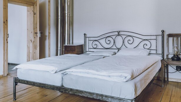 A bed with a metal frame, a wooden floor, and a white wall. - Riverside Flat for Two Guests (Janowice Wielkie)