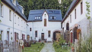 A courtyard with a cobblestone path leading to a building with a gabled roof and a central tower. - Riverside Flat for Two Guests (Janowice Wielkie)