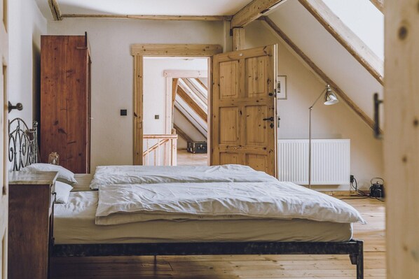 Ein Schlafzimmer mit einem hölzernen Bett, einem Nachttisch, einem Schreibtisch und einer Heizung.