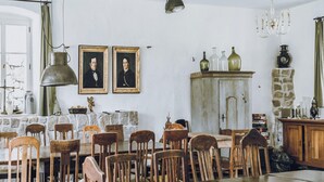 Un coin repas agrémenté d’un mur en pierre, de chaises en bois, d’une table en bois et d’un lustre ancien.