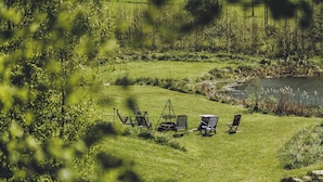 Un espace extérieur verdoyant, avec un étang, entouré d’arbres et de végétation.