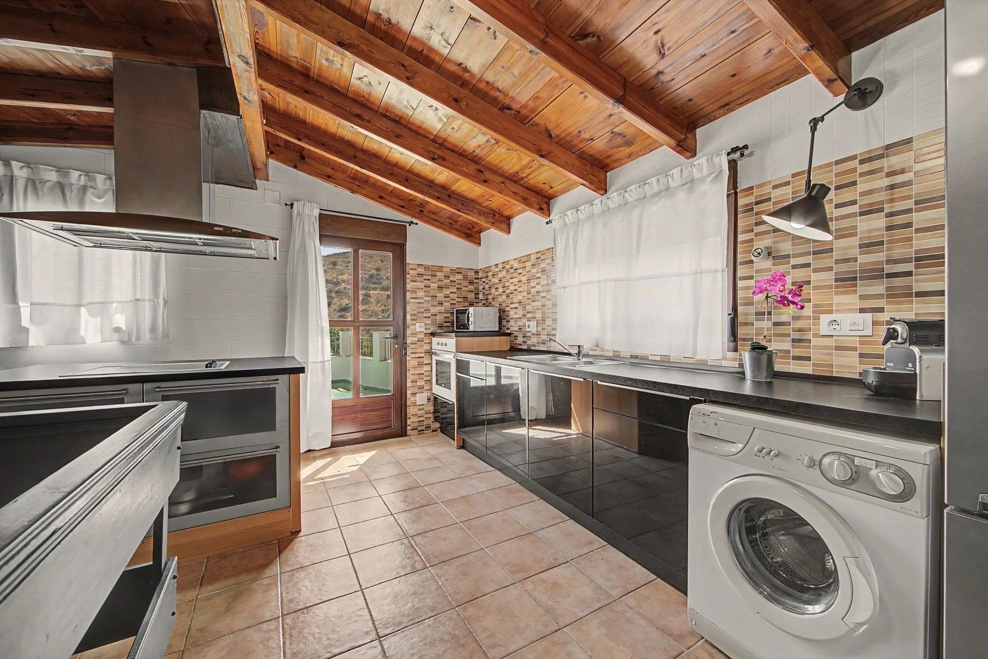 A compact kitchen with a built-in oven, a washing machine, and a microwave.