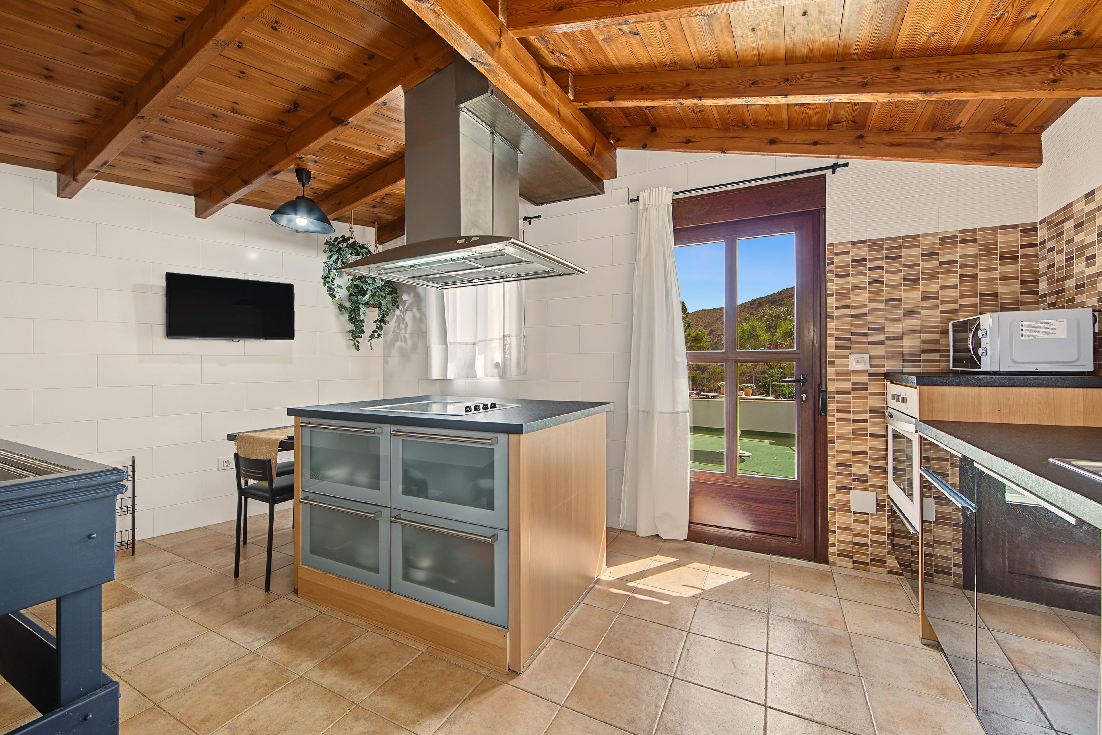 Una cocina moderna con una isla central, horno empotrado y microondas.