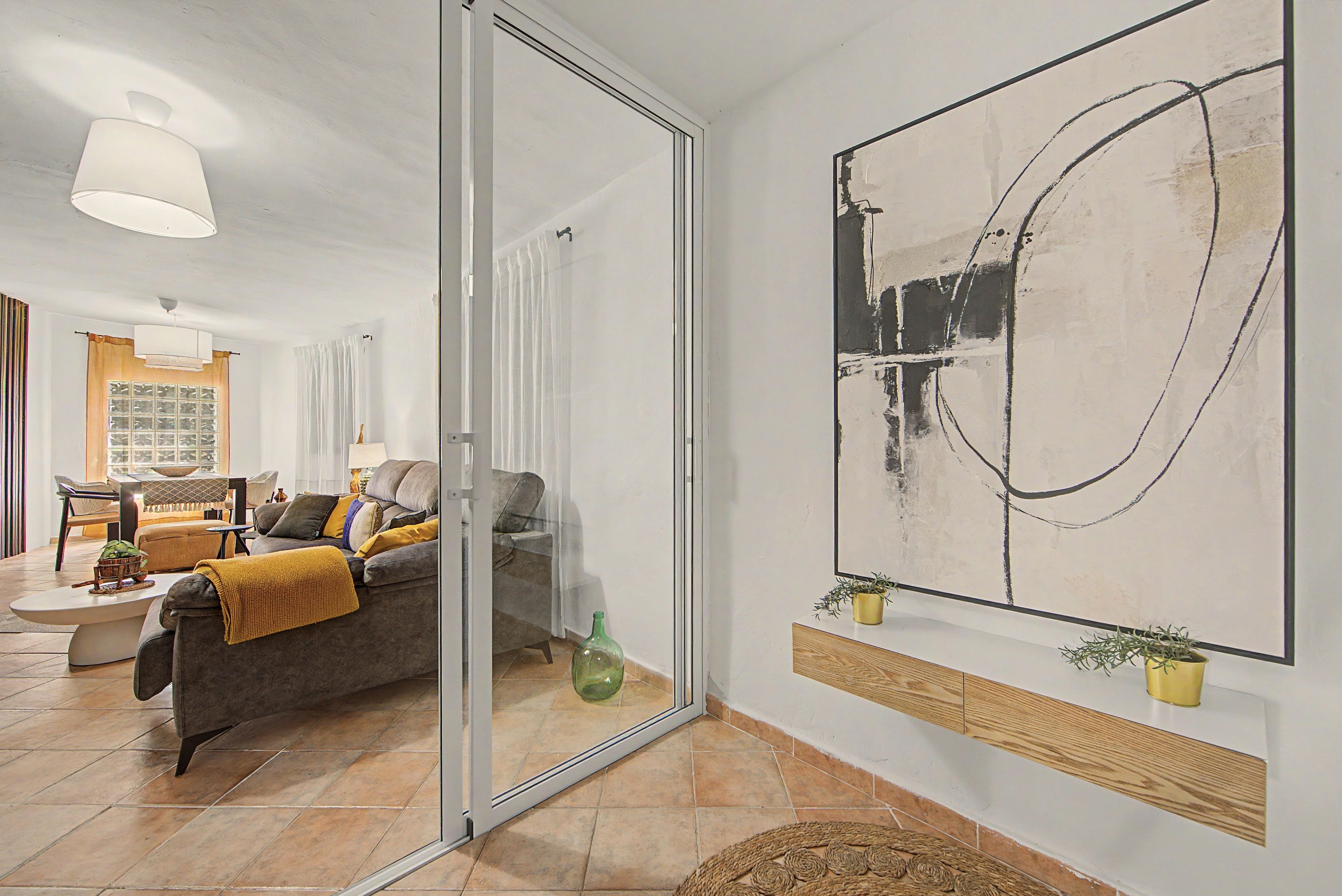 Una sala de estar moderna con un sofá, una mesa de centro y un cuadro abstracto grande en la pared.