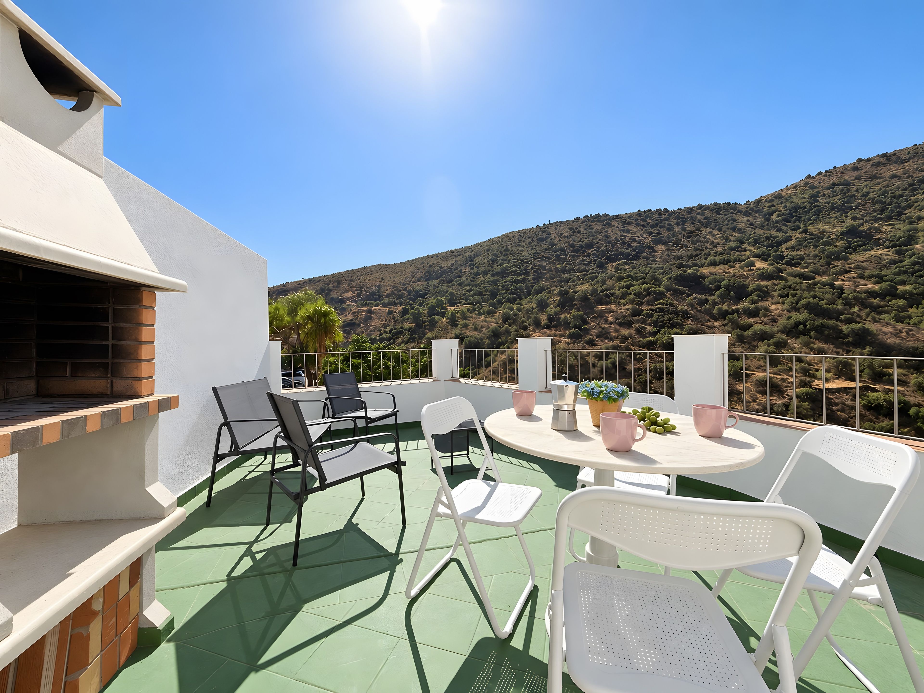 Une terrasse avec des sièges extérieurs, un espace barbecue et une vue sur un paysage vallonné.