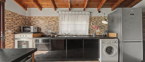 A compact kitchen with a built-in oven, microwave, and a washing machine.