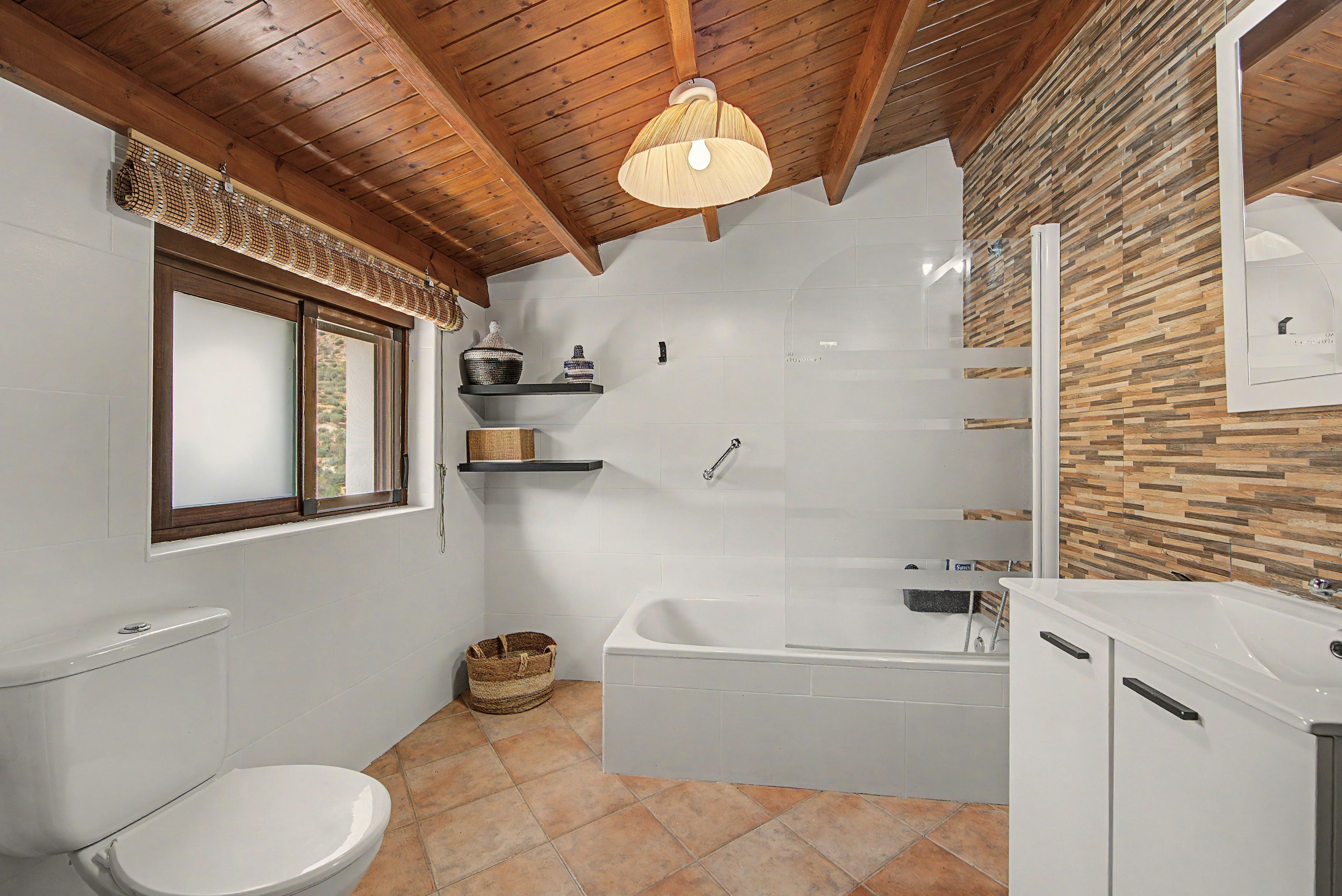 Een badkamer met toilet, douche, wastafel en raam.