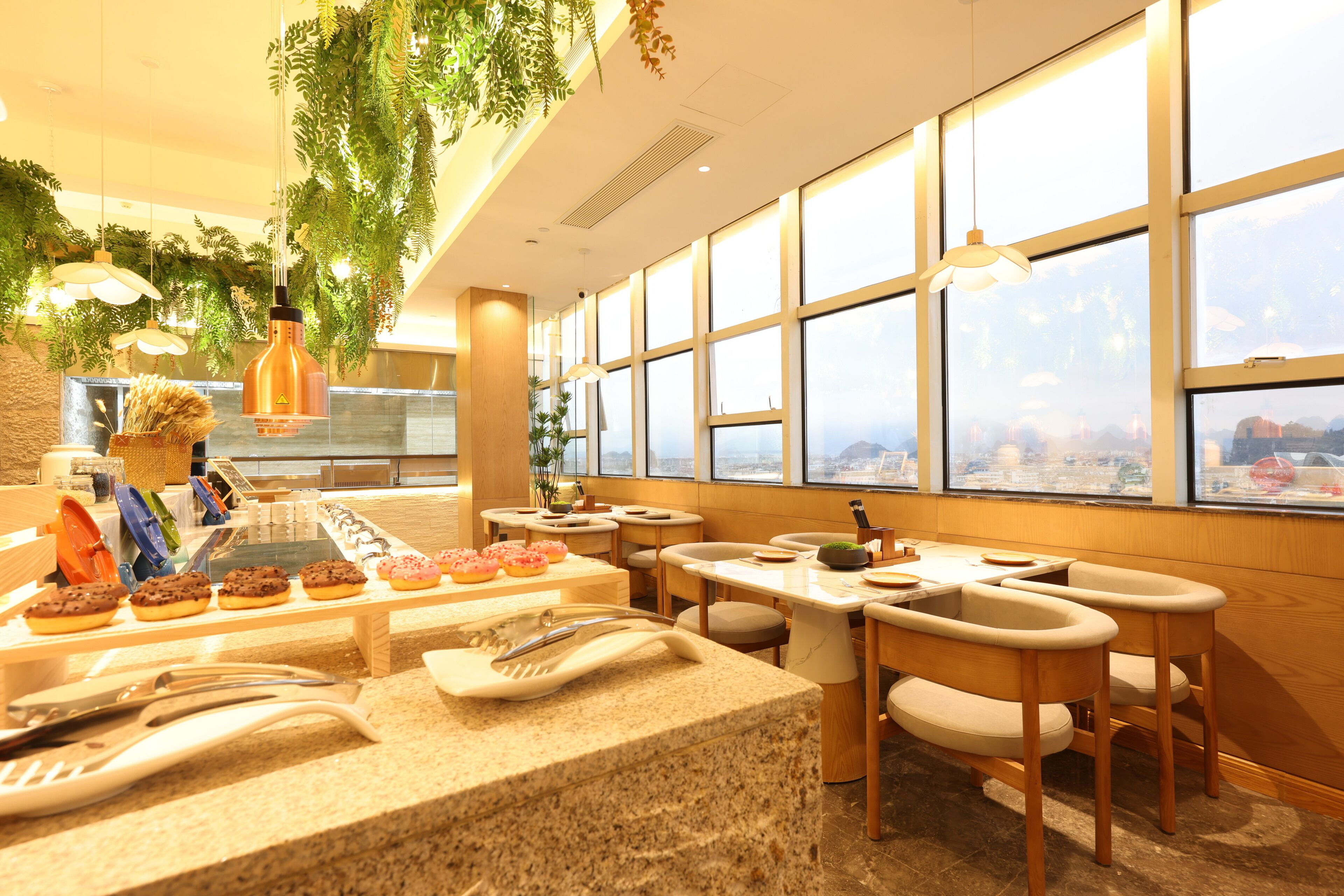 Un restaurant moderne avec un intérieur élégant, comprenant un buffet, un espace repas et de grandes fenêtres offrant une vue sur la ville.