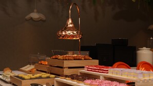 Variedad de pasteles y productos de panadería exhibidos en pedestales de madera.