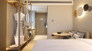 Habitación de hotel con una cama grande, una mesa redonda con un bol, un sofá, un espejo y un armario.