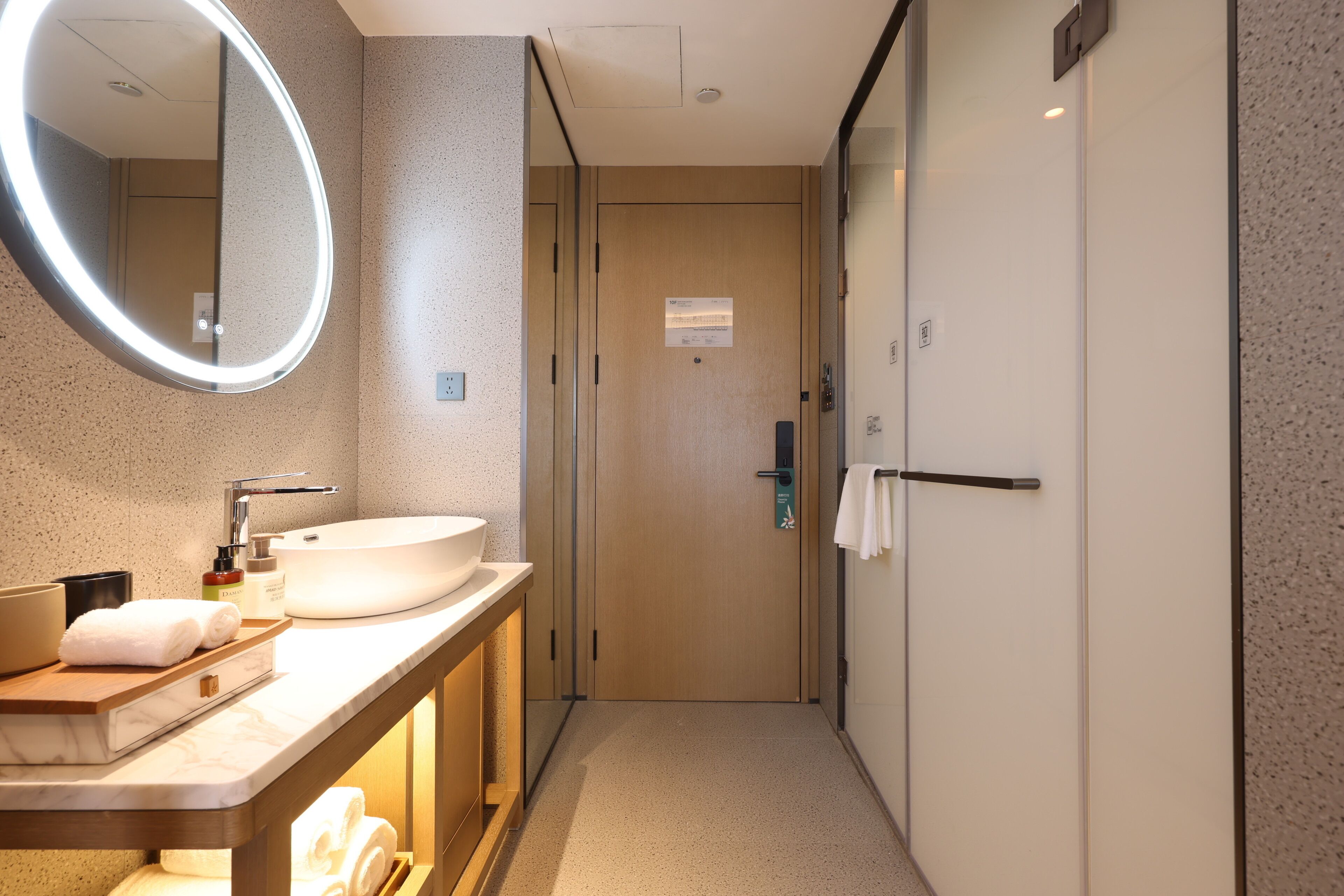 Un baño de hotel con encimera de mármol, un lavamanos, un espejo y un perchero para toallas.