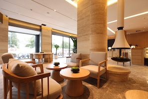 A modern interior with seating arrangements, a large pillar, and a kitchen area.