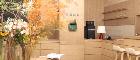 A modern reception area with a wooden reception desk, a vase with flowers, and a wall-mounted sign.