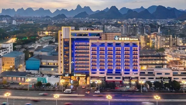 Un hotel de varios pisos, estacionamiento y vistas a montañas distantes.