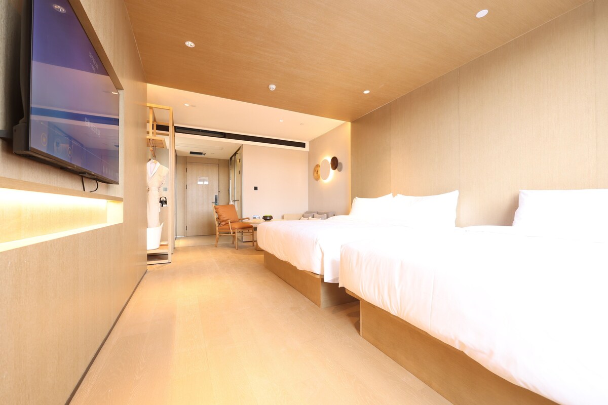 A hotel room with a bed, a chair, a desk, and a television mounted on the wall.
