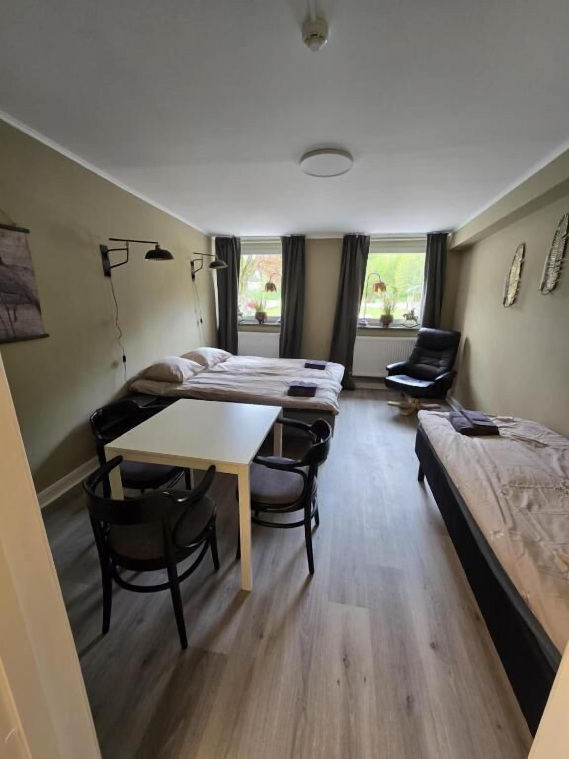A compact room with a bed, a desk, and two chairs.