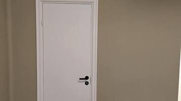En stängd vit dörr med ett svart handtag, en vit bänk och en beige vägg.
