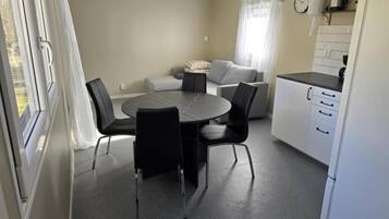 Un ambiente compatto con tavolo da pranzo, sedie, divano e angolo cottura.