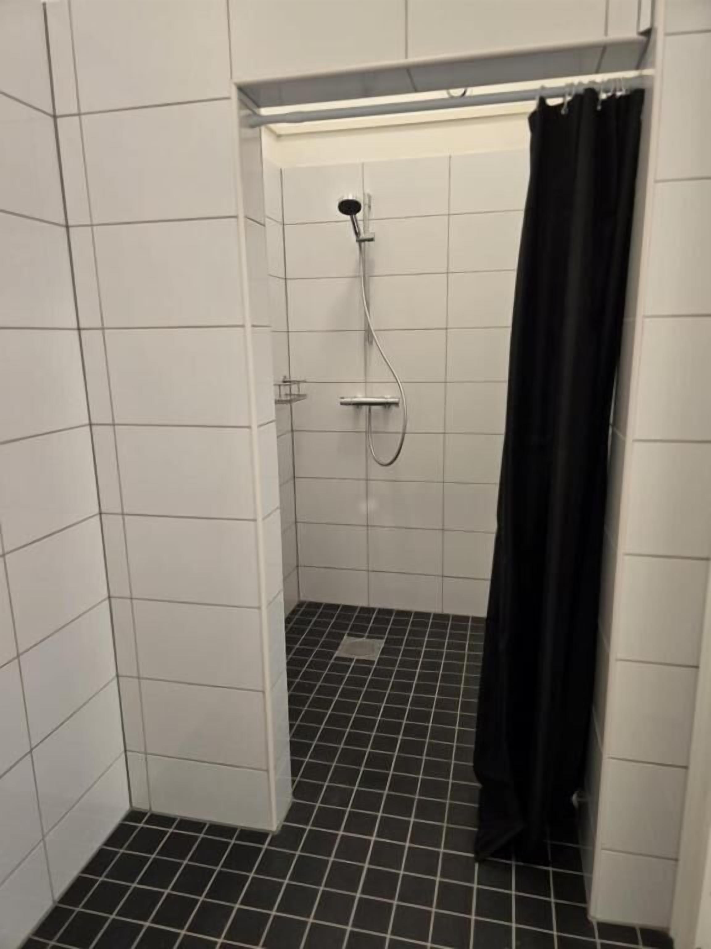 A small, enclosed shower area with a showerhead and curtain.