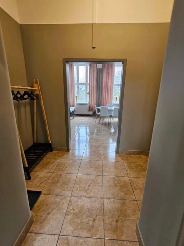 Un pasillo que conduce a una habitación con ventana, perchero y puerta.