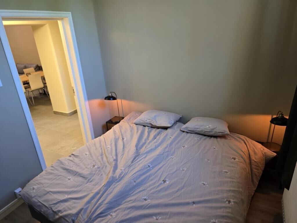 Un dormitorio con una cama, dos mesitas de noche y un tocador.