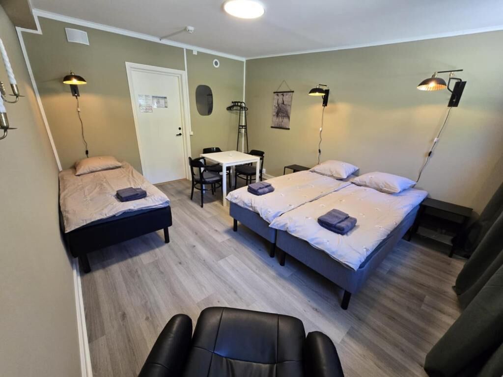 A room with two beds, a table, chairs, and a desk.