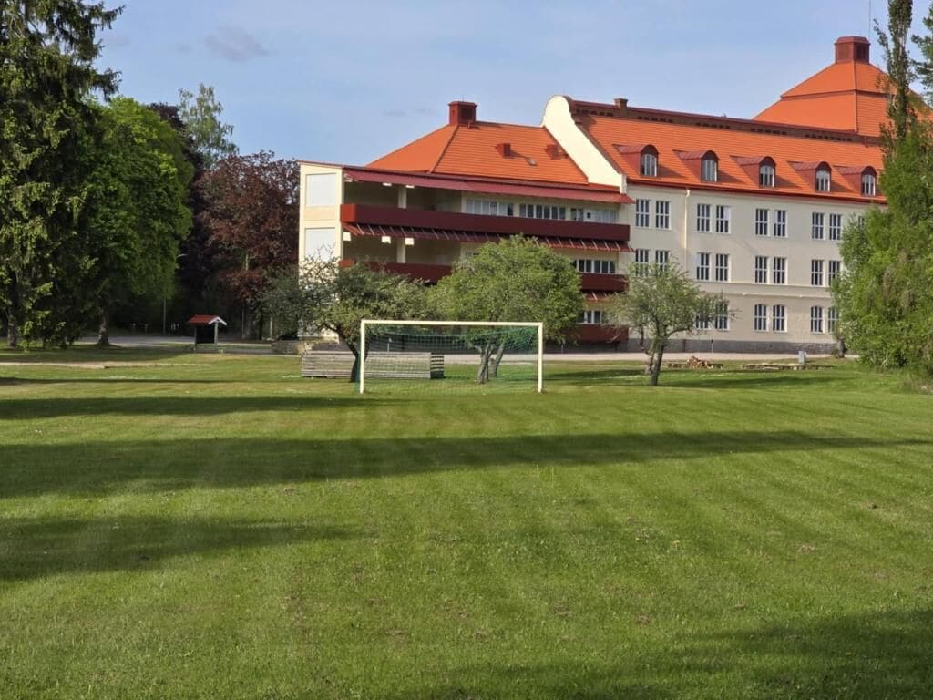 Um edifício com telhado vermelho e um campo gramado na frente.