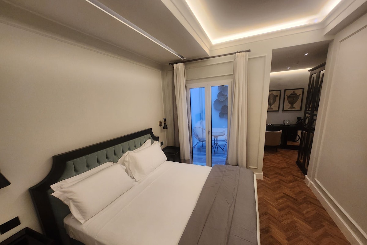 A hotel room with a bed, a nightstand, a desk, and a view of a balcony.