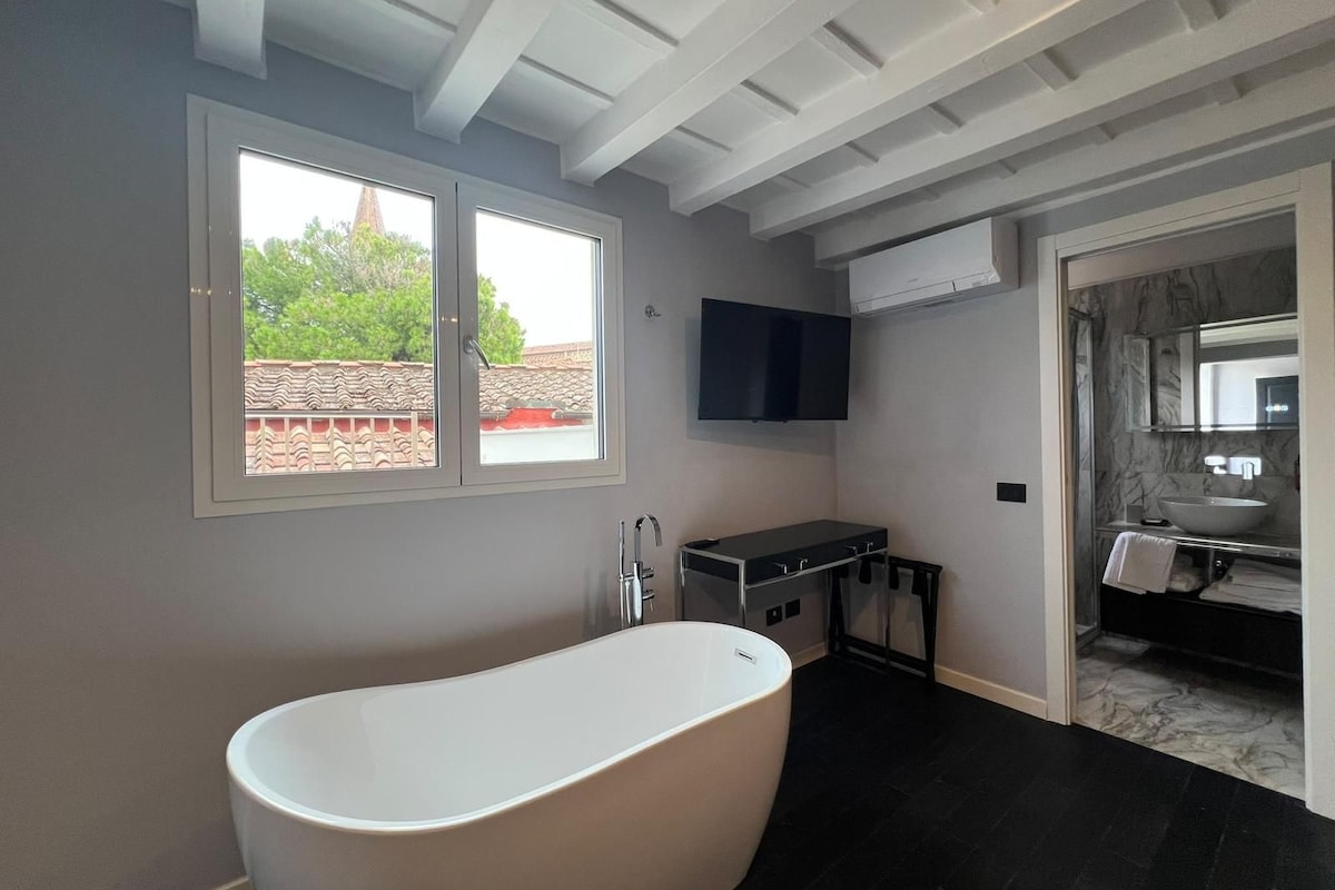 A modern bathroom with a freestanding bathtub, a vanity with a mirror, and a large window.