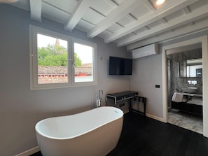 A modern bathroom with a freestanding bathtub, a vanity with a mirror, and a large window. - Vivaldi Boutique hotel (Florence)