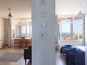 A spacious room with a dining area, a bed with a view, and a large window. - 16 Old Shipyard Centre (Bridport)