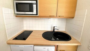 A compact kitchenette with a microwave, sink, and dishwasher. - Studio for 4 people at the entrance to Méribel Mottaret (LES ALLUES)