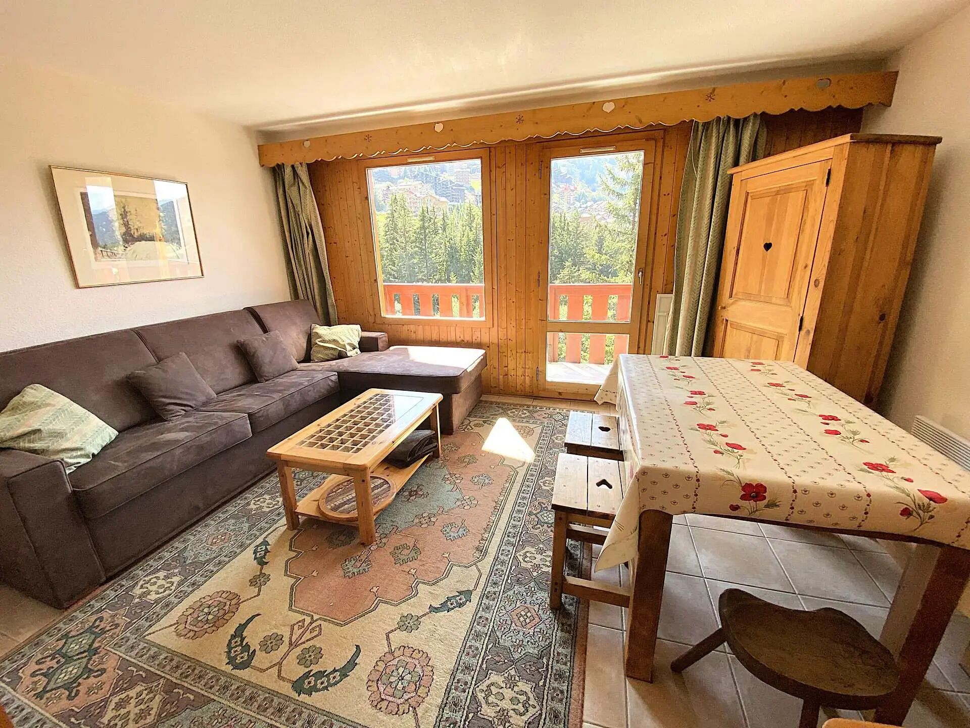A cozy living room with a sofa, a coffee table, a dining table, and a view of a balcony.