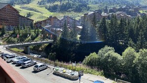 A mountain town with a bridge, parking area, and buildings with visible signage. - Studio for 4 people at the entrance to Méribel Mottaret (LES ALLUES)