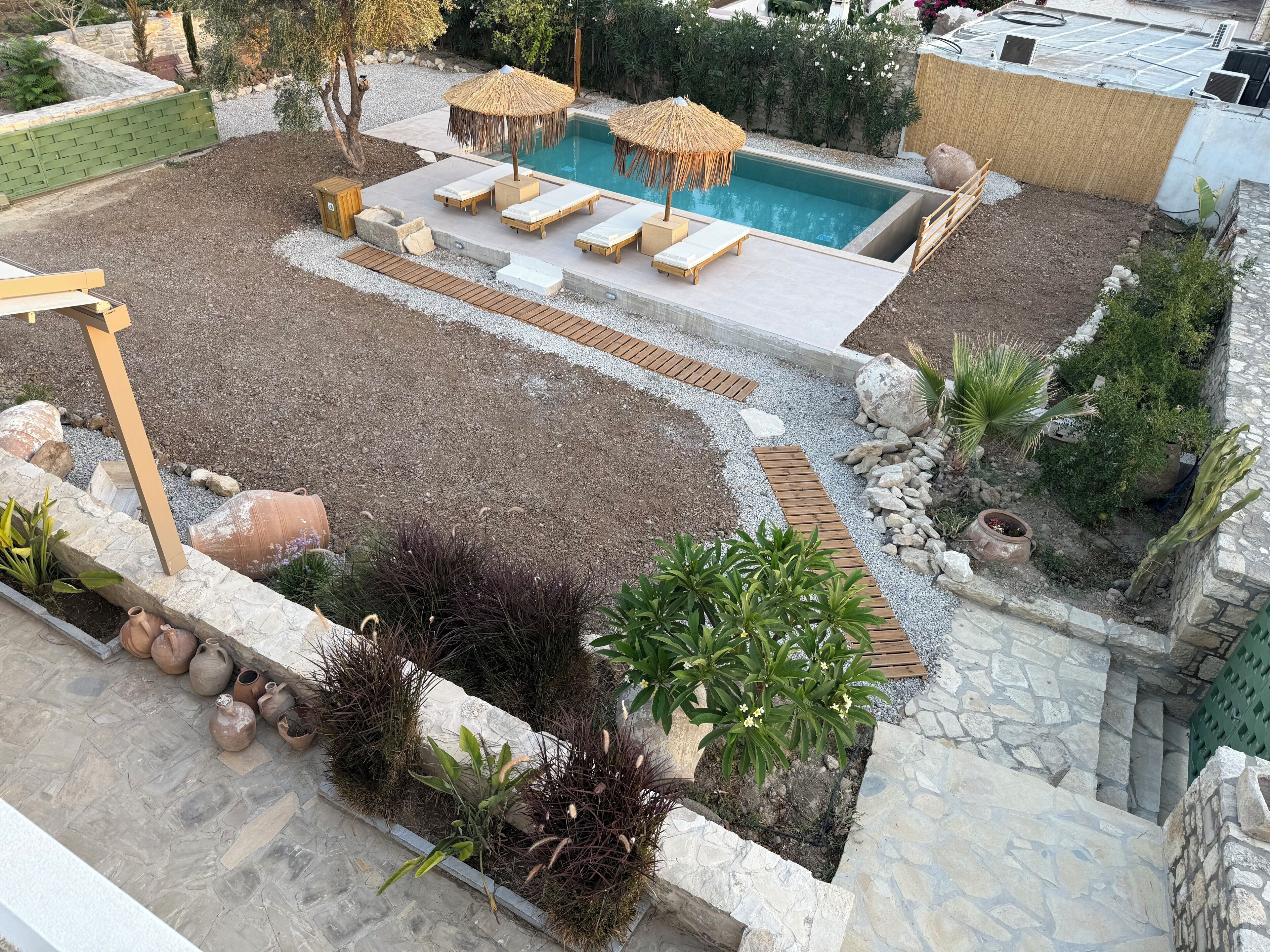 Área de piscina en la azotea con sillones de descanso y una piscina pequeña, rodeada por un patio de grava y diversas plantas.