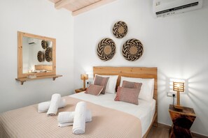 A hotel room with a bed, a mirror, wall art, and bedside lamps. - Villa Papadia with Private Pool – Pitsidia, South Crete (Iraklio)