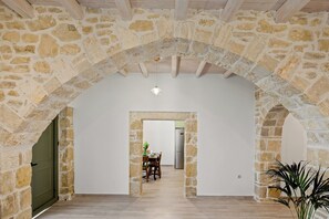 A stone archway leading to a dining area with a table and chairs, a hanging light fixture, and a potted plant. - Villa Papadia with Private Pool – Pitsidia, South Crete (Iraklio)