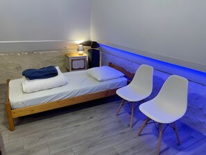 A single bed with a nightstand, two white chairs, and a lamp. - Converted Barn on Large Natural Estate (Monfaucon)