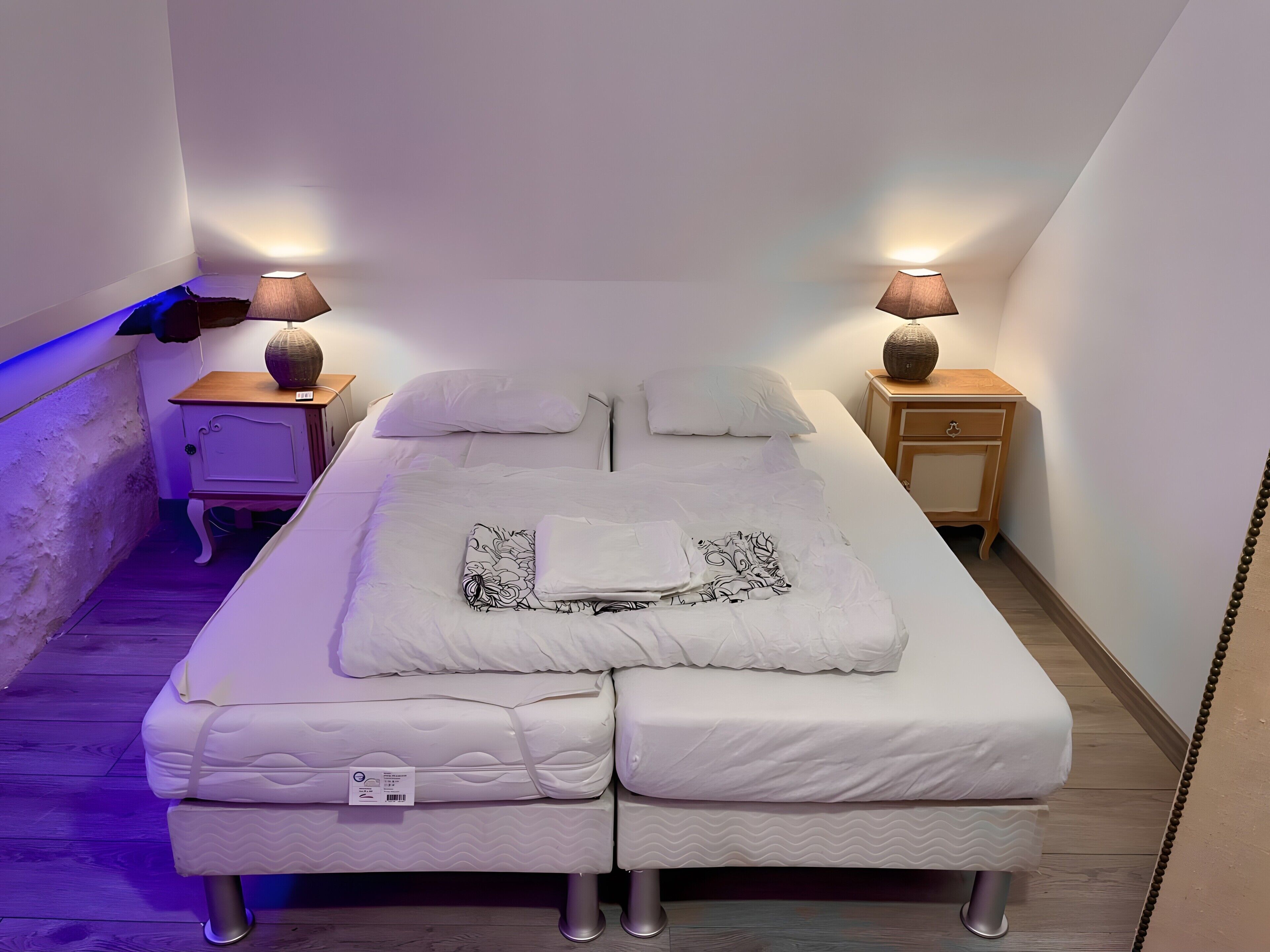 A narrow room with a single bed, two bedside tables, and two lamps.