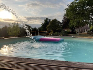 Ein Schwimmbecken mit einer schwimmenden Plattform und einem hölzernen Deck im Vordergrund.