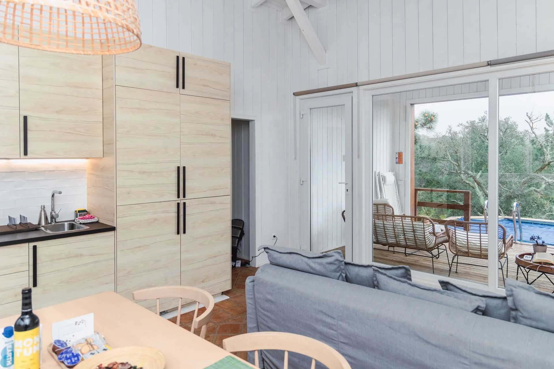 Una cocina moderna con gabinetes de madera y un comedor con sofá y sillas grises.