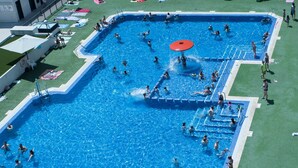 A large outdoor swimming pool with multiple lanes, surrounded by a grassy area and a few lounge chairs. - Apartment 'Beach' with Sea View, Wi-Fi and Air Conditioning (Alboraya)