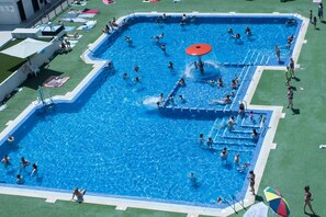 A large outdoor swimming pool with multiple lanes, surrounded by a grassy area and a few lounge chairs. - Apartment 'Beach' with Sea View, Wi-Fi and Air Conditioning (Alboraya)