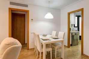 A dining area with a table set for four, white chairs, a white pendant light, and a wooden door. - Apartment 'Beach' with Sea View, Wi-Fi and Air Conditioning (Alboraya)