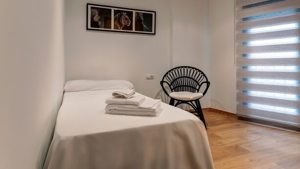 A bedroom with a bed, a chair, and a window with blinds. - Apartment 'Beach' with Sea View, Wi-Fi and Air Conditioning (Alboraya)